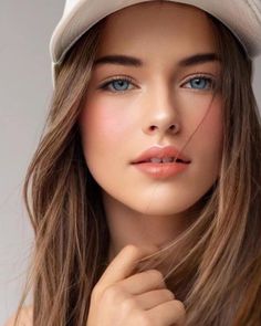Woman with blue eyes and long brown hair wearing a white hat