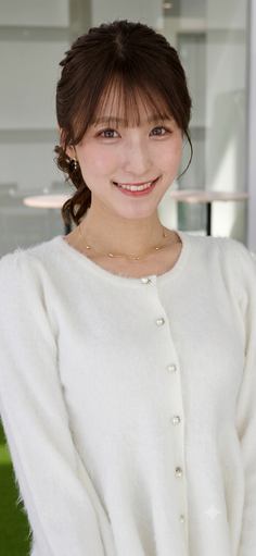 Woman with brown hair in an updo wearing a white cardigan and gold necklace