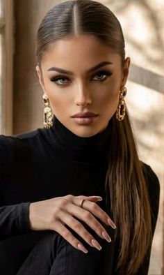 Woman with long hair and gold earrings wearing a black turtleneck