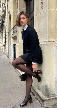 Woman in a black dress and polka dot tights posing on a city street