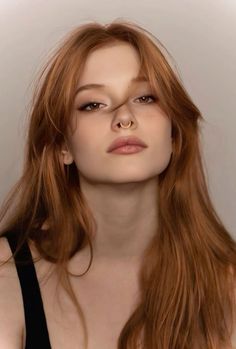Woman with long red hair and a septum ring looking directly at the viewer