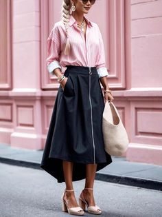 Woman with braided blonde hair wearing a pink shirt and black skirt outdoors