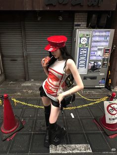 Woman in a red hat and black shorts standing on a street next to a vending machine