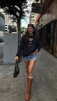 Woman in a denim skirt and brown boots walking on a city street