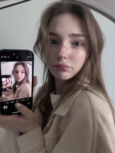 Woman with long hair holding a phone to take a mirror selfie