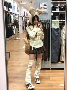 Young woman in a bunny hat and pleated skirt taking a mirror selfie in a store