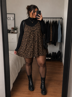 Woman in a leopard print dress over a black turtleneck, black tights, and chunky boots