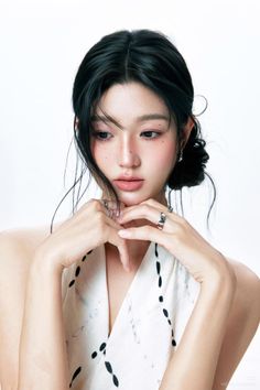 Woman with black hair in an updo, wearing rings, against a white background