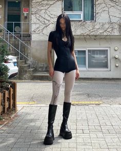 Woman with long black hair in a black bodysuit and platform boots on a street