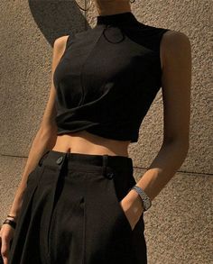 Person in a black crop top and pants with exposed midriff outdoors