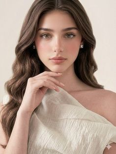 Woman with long wavy hair and green eyes, wearing diamond earrings