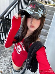 Woman in a red top and camo hat with an exposed midriff outdoors
