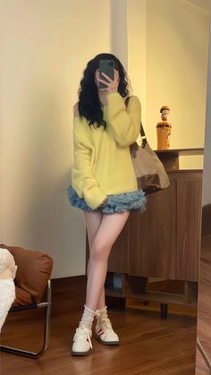 Person in a yellow sweater and ruffle skirt taking a mirror selfie