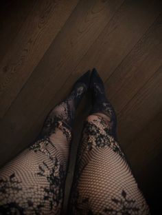 Legs in black fishnet stockings and heels on a wooden floor