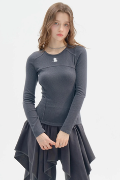 Woman in a dark gray long sleeve shirt and asymmetrical skirt