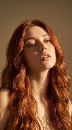 Woman with long red hair and green eyes in soft, warm lighting