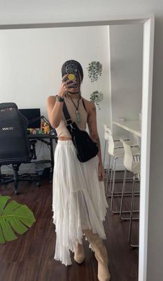 Person in a crop top and long skirt taking a mirror selfie indoors