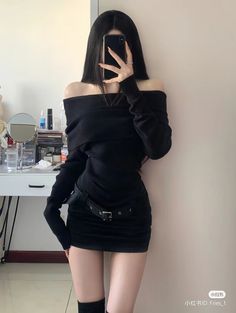 Woman in a black off-shoulder mini dress taking a mirror selfie
