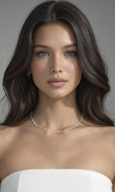 Woman with long dark hair and blue eyes wearing a delicate necklace
