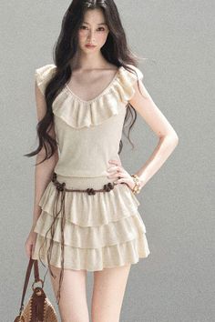 Woman with long dark hair wearing a ruffle top and tiered skirt with a beaded belt
