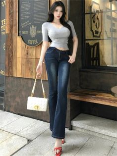 Woman with long black hair wearing a cropped top and flared jeans outdoors