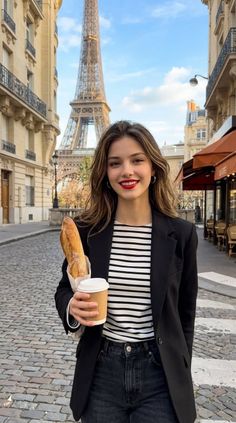 Woman holding a baguette and coffee on a cobblestone street with the Eiffel Tower in the background