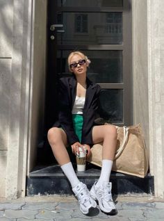 Woman with blonde hair and sunglasses sitting outdoors with a coffee cup