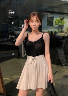Woman in a black tank top and mini skirt standing outdoors