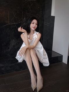Woman in a white dress and pantyhose sitting indoors