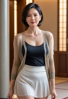 Woman with short hair wearing a cardigan, black top, and white mini skirt indoors