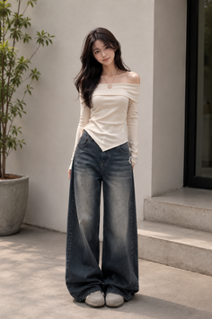 Woman with long dark hair wearing an off-shoulder top and wide-leg jeans outdoors