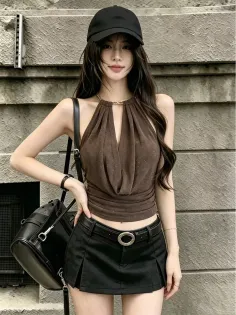 Woman in a black cap, brown halter top, and black mini skirt outdoors