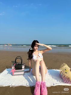 Woman in a bikini sitting on a white towel at the beach