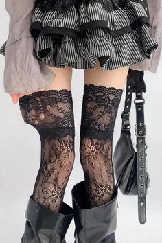 Person wearing black lace stockings, a striped skirt, and black boots