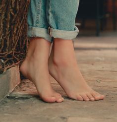 Bare feet and cuffed blue jeans on a wooden floor