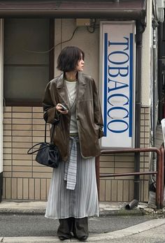 Woman with short hair wearing a leather jacket and striped skirt on a street
