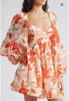 Woman wearing a white dress with orange floral print and cut-out details