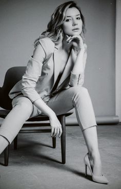 Woman in a suit and high heels posing on a chair in a studio