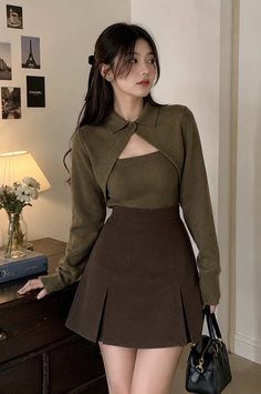 Woman in a brown skirt and green cropped cardigan indoors
