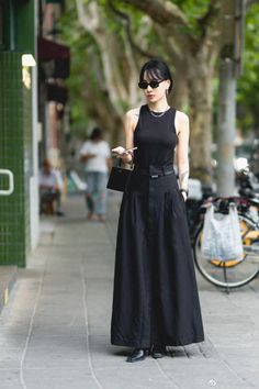 Woman in a black sleeveless top and long skirt on a city street