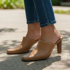 Person wearing brown mules and blue jeans outdoors in daylight