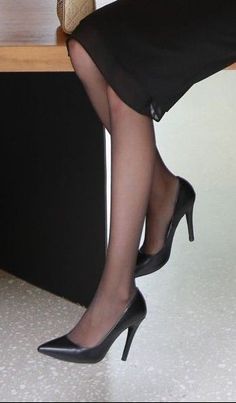 Woman's legs in black dress and high heels, wearing pantyhose