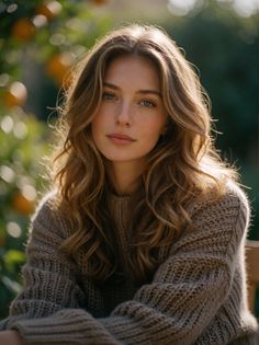 Woman with long wavy hair and green eyes wearing a knitted sweater outdoors