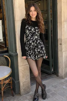 Woman in a floral dress and polka dot tights standing outdoors