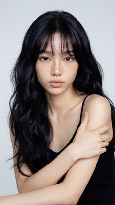Woman with long black hair and freckles wearing a black tank top