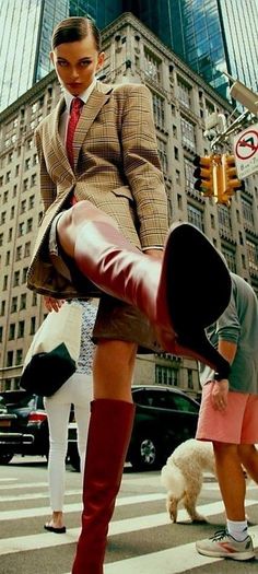 Woman in a plaid blazer and red boots on a city street from a low angle