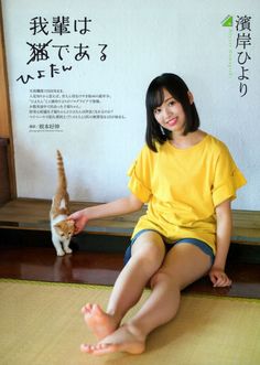 Woman in a yellow t-shirt and denim shorts petting a kitten indoors