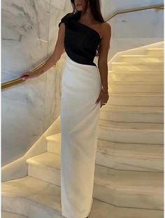 Woman in a black and white one-shoulder long dress on a marble staircase