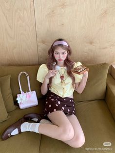 Woman with long hair and a headband sitting on a couch with a dessert