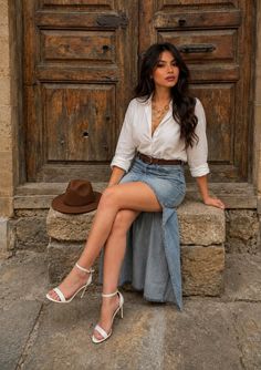 Woman in a denim skirt and white shirt sitting on stone steps